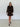Woman wearing a brown patterned dress standing in a white room.