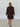 Person wearing a brown patterned outfit standing against a white wall.